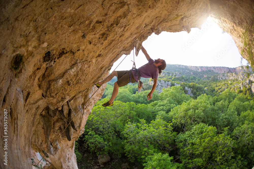 Rock climber climbs into the cave, Rock in the form of an arch