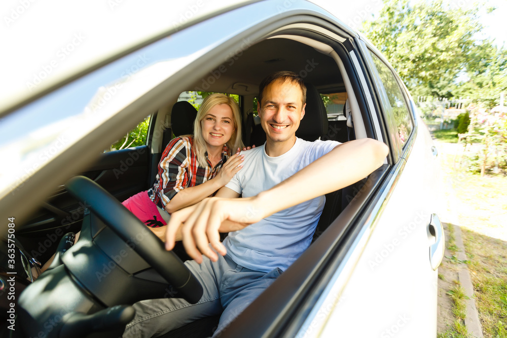 Happy young man and woman in a car enjoying a road trip on a summer day.