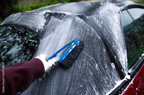 Quadro su tela cleaning the tarpaulin roof of the convertible with foam cleaner.