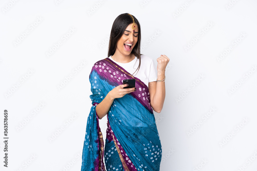 Young Indian woman isolated on white background with phone in victory position Young Indian woman isolated on white background with phone in victory position