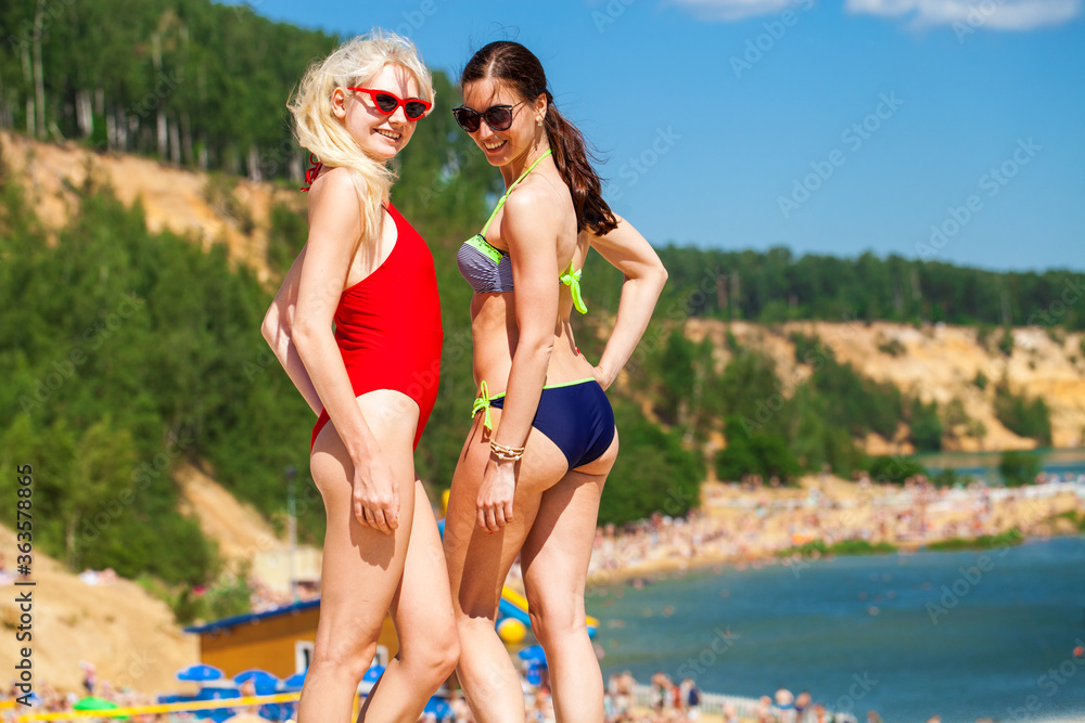 Portrait of two young girls in swimsuits posing on the beach