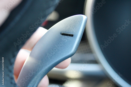 Fingers on gear shift pedal of a sports car steering wheel