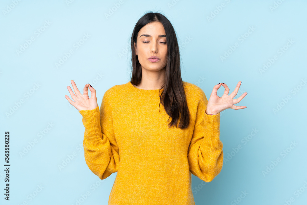 Young caucasian woman isolated on blue background in zen pose - obrazy, fototapety, plakaty 