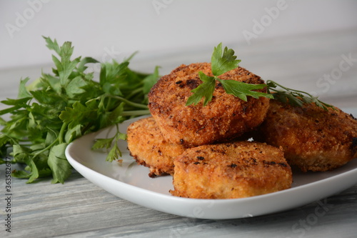 Juicy fried homemade chicken cutlets. Coated with breadcrumbs, delicious, in white dish with herbs. On old wooden background, rustic style
