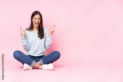 Young caucasian woman isolated on pink background making rock gesture