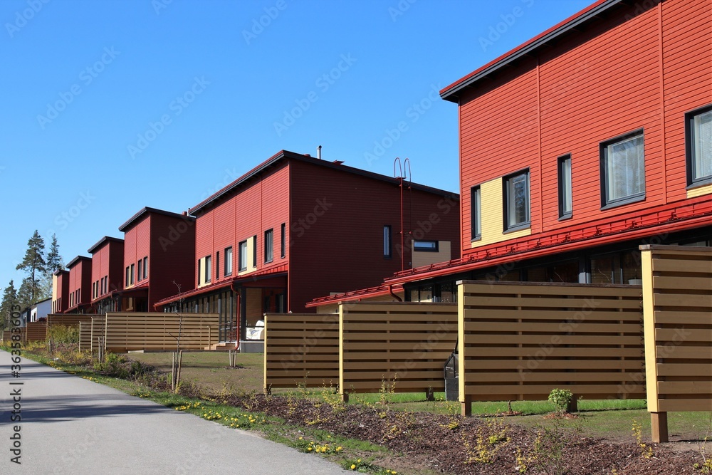 Cozy red row houses with small gardens in a suburb. Wooden fences between the neighbours provide some privacy. Scandinavian architecture. The photo is taken in Vantaa, Finland. Selective focus. Cozy red row houses with small gardens in a suburb. Wooden fences between the neighbours provide some privacy. Scandinavian architecture. The photo is taken in Vantaa, Finland. Selective focus.