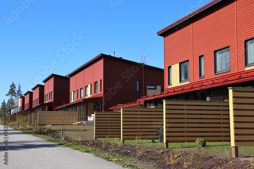 Cozy red row houses with small gardens in a suburb. Wooden fences between the neighbours provide some privacy. Scandinavian architecture. The photo is taken in Vantaa, Finland. Selective focus.