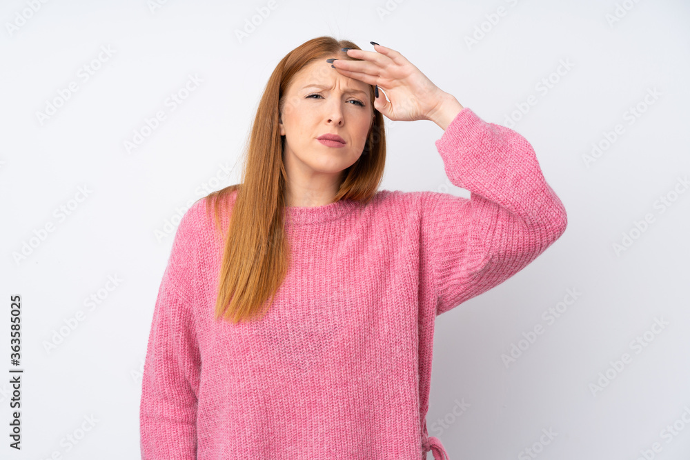 Young redhead woman with pink sweater over isolated white background looking far away with hand to look something Young redhead woman with pink sweater over isolated white background looking far away with hand to look something