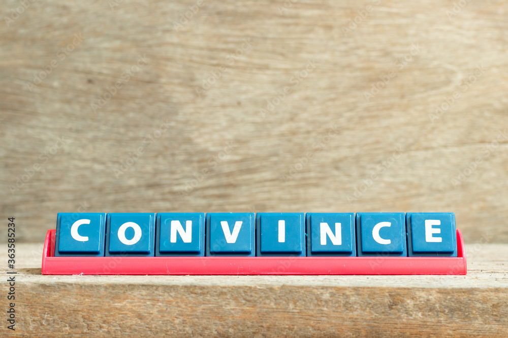 Tile letter on red rack in word convince on wood background Tile letter on red rack in word convince on wood background