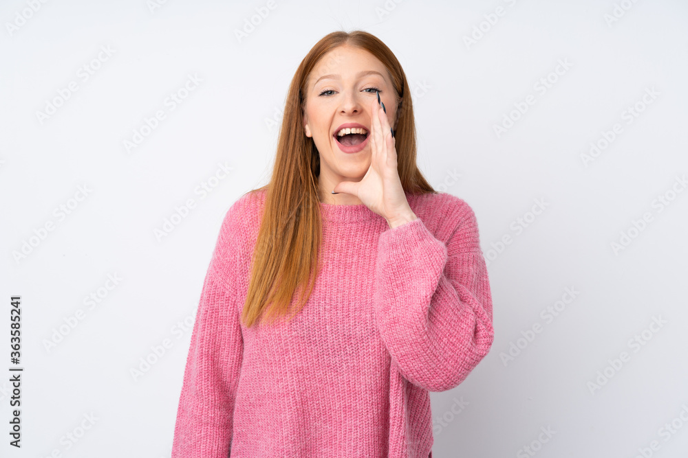 Young redhead woman with pink sweater over isolated white background shouting with mouth wide open Young redhead woman with pink sweater over isolated white background shouting with mouth wide open