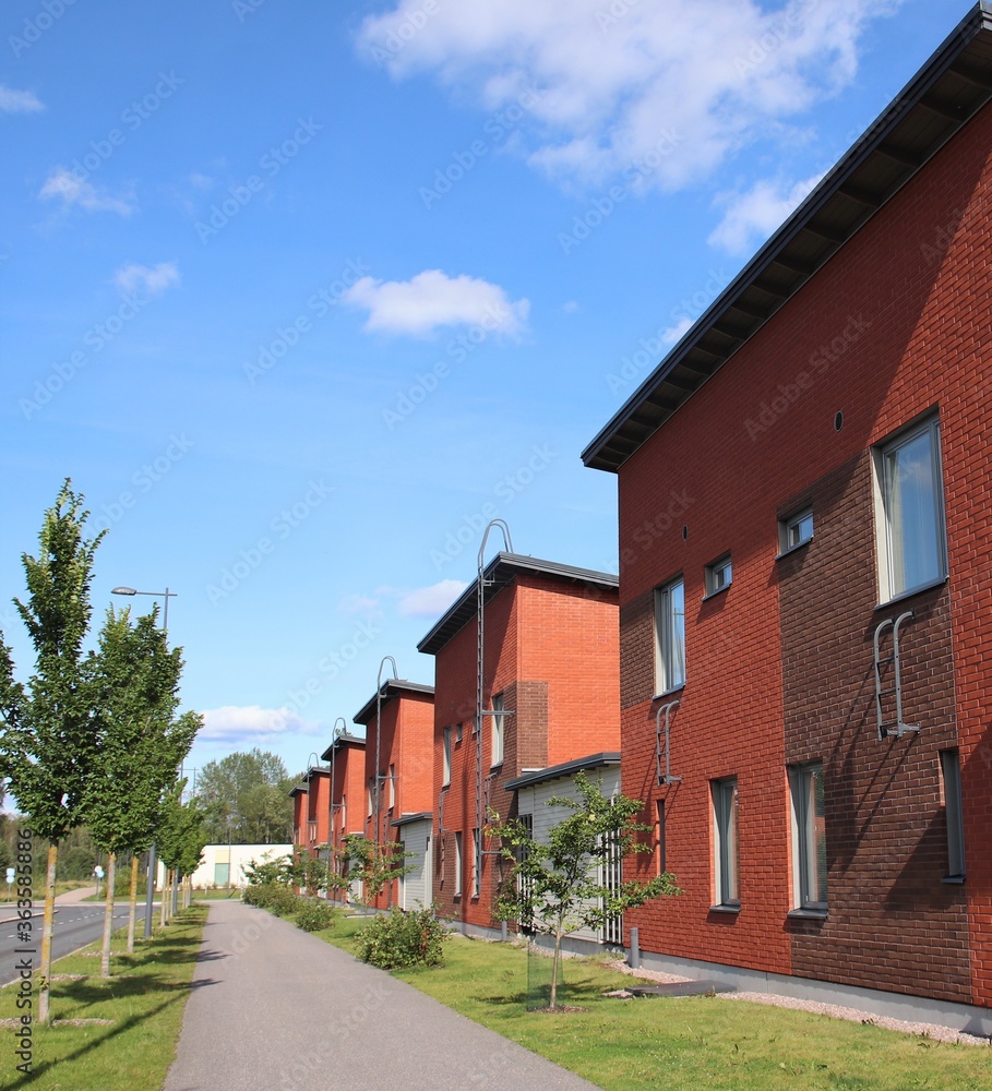 A suburban street with red houses on a perfect summer day. Scandinavian architecture. The photo is taken in Espoo, Finland. A suburban street with red houses on a perfect summer day. Scandinavian architecture. The photo is taken in Espoo, Finland.