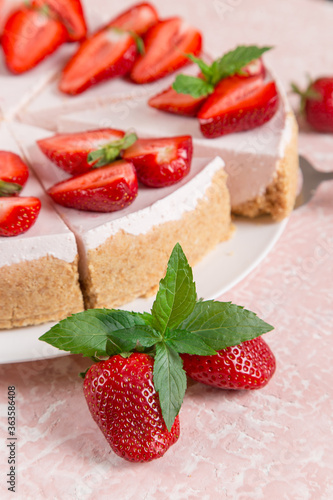 Sweet breakfast, delicious cheesecake with fresh strawberries and mint, homemade recipe without baking, on a pink stone table. Copy space.