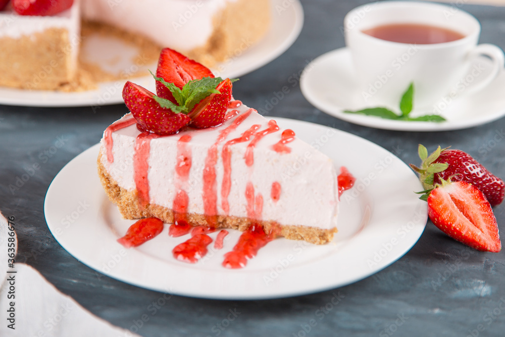 Sweet breakfast, tea and delicious cheesecake with fresh strawberries and mint, homemade recipe without baking, on dark blue stone table. Copy space. Sweet breakfast, tea and delicious cheesecake with fresh strawberries and mint, homemade recipe without baking, on dark blue stone table. Copy space.