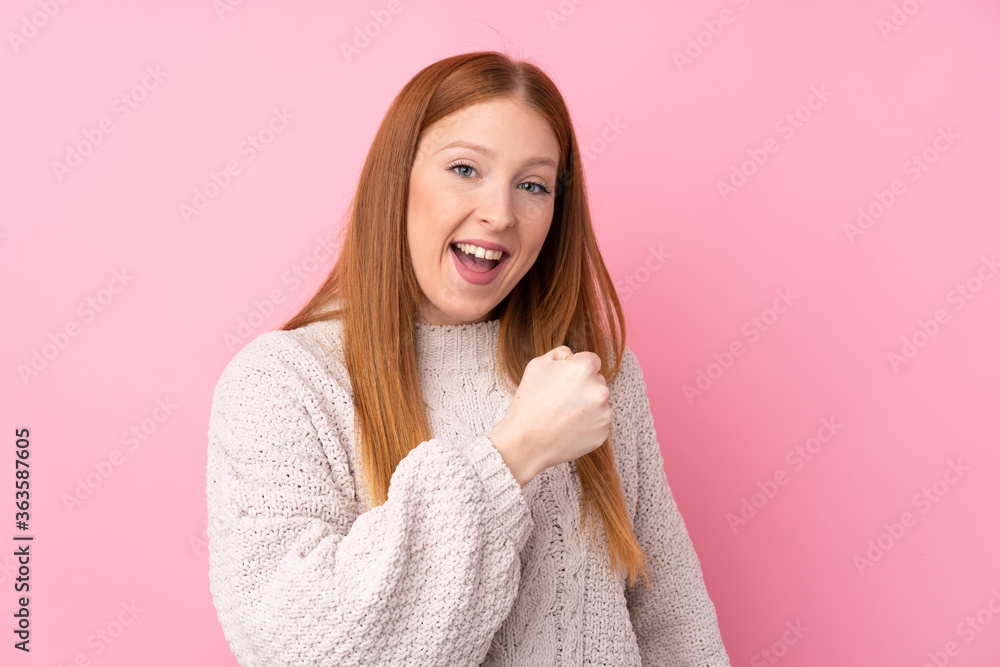 Young redhead woman over isolated pink background celebrating a victory Young redhead woman over isolated pink background celebrating a victory