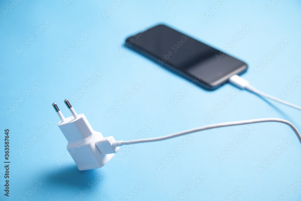 Smartphone with a charger on the blue background. Smartphone with a charger on the blue background.