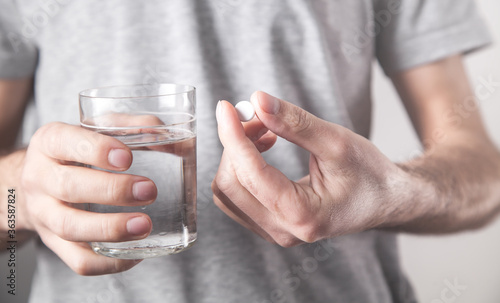 Man holding glass of water and tablet.