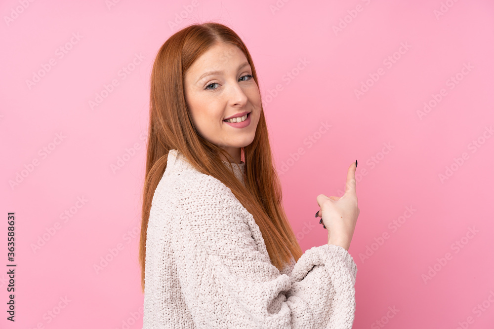 Young redhead woman over isolated pink background pointing back Young redhead woman over isolated pink background pointing back
