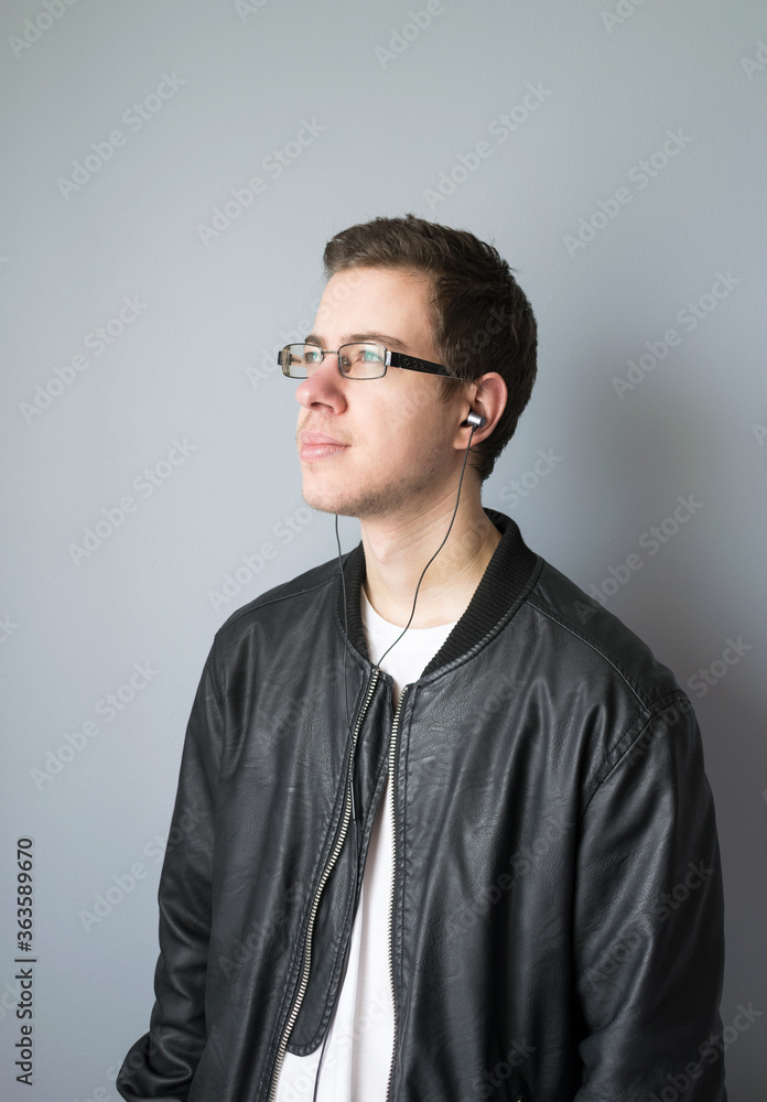 Fototapeta premium Portrait of young man with glasses looking to the side with earphones