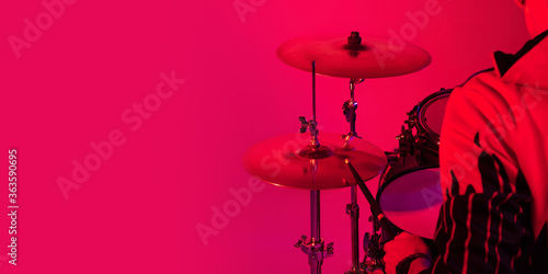 Cropped. Young inspired and expressive musician, drummer performing on gradient colored background in neon light. Concept of music, hobby, festival, art. Joyful artist, colorful, bright portrait. © master1305