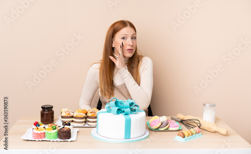 Young redhead woman with a big cake whispering something