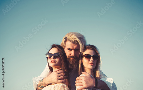 Portrait of happy man between two girls standing on sky background on summer vacation. photo