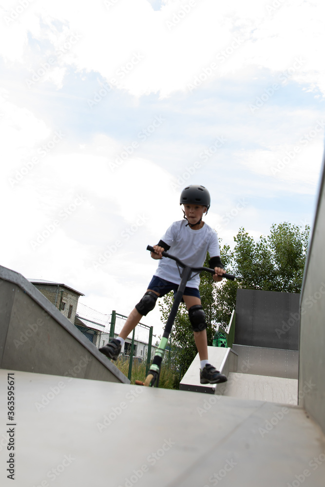 The boy jumps on a scooter.