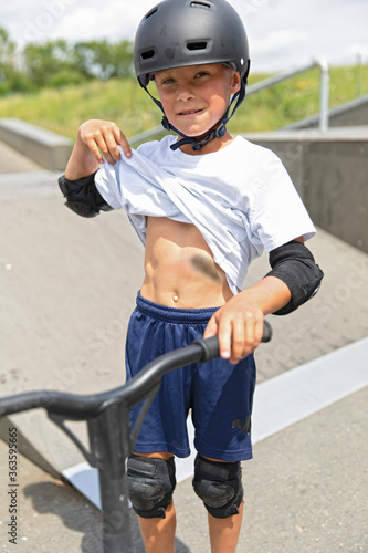 Obraz na płótnie A cute little boy rides a scooter in a skatepark. w salonie