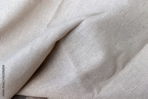 Natural beige linen fabric texture. Rough crumpled burlap background. Selective focus. Closeup view