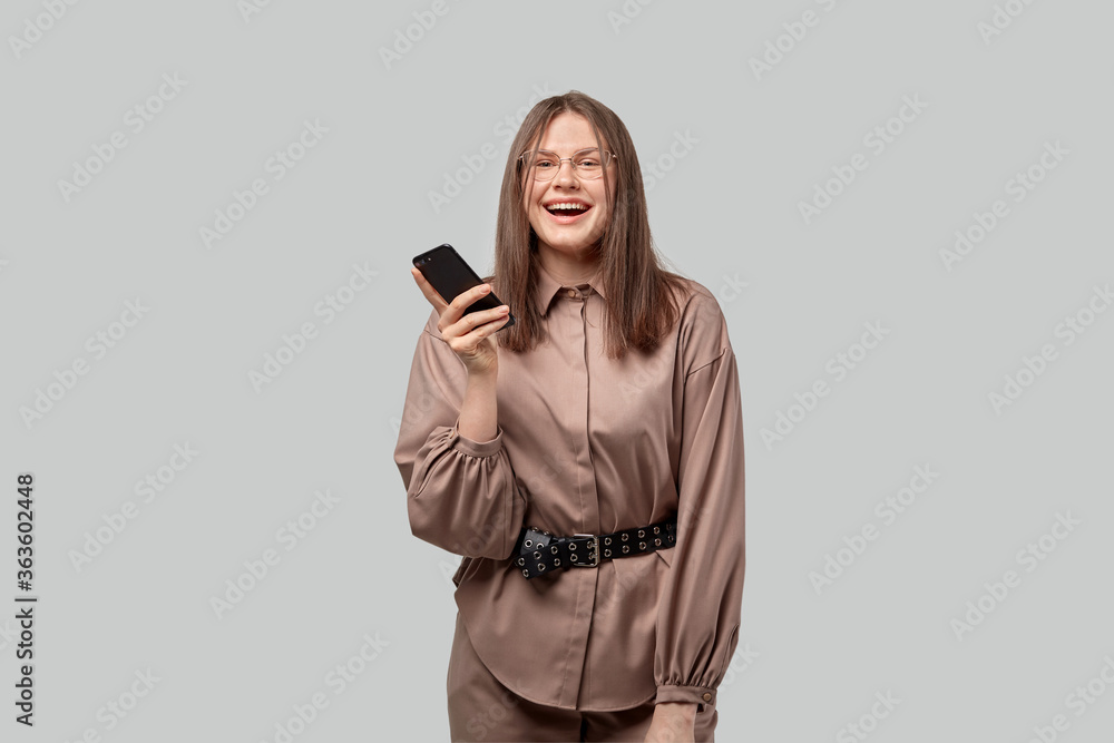The brunette in glasses holds the phone in her hands and smiles. The brunette in glasses holds the phone in her hands and smiles.