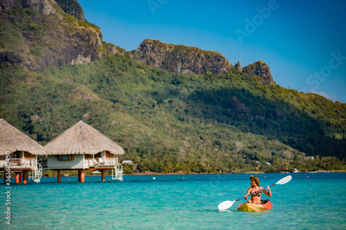Tableau sur toile Woman paddling a kayak by the tropical beach.