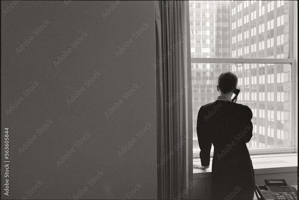 Woman on phone standing in window, NYC in background Woman on phone standing in window, NYC in background