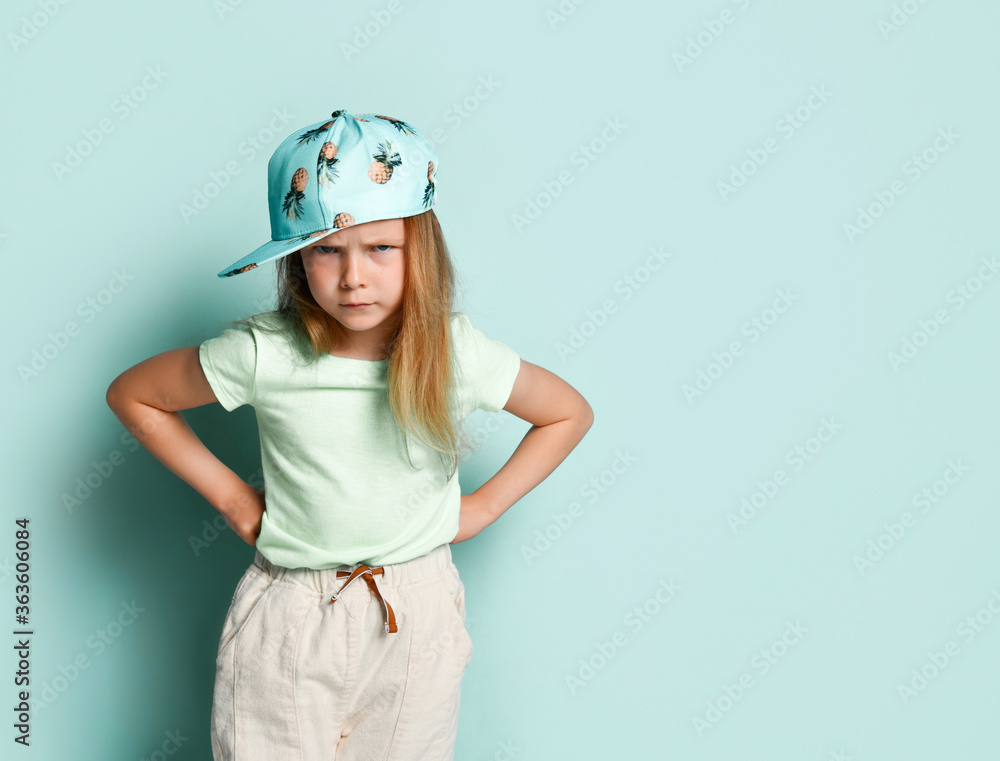 Fotografia Upset little girl standing with hands on hips, bending brows and looking angrily
