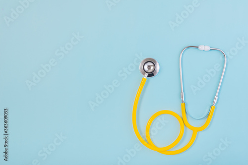 Yellow stethoscope isolated on blue background with copy space for text.