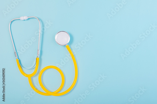 Yellow stethoscope isolated on blue background with copy space for text.
