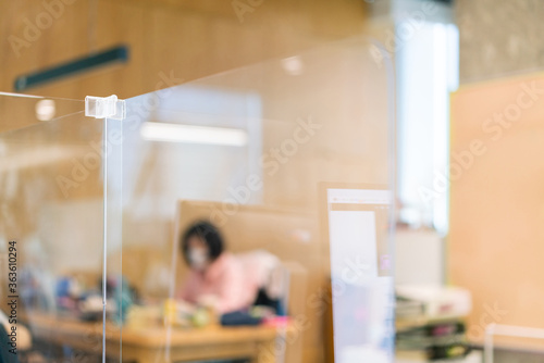 Foto Acrylic plexiglass separator setting on the desk in the office with blur employee wearing mask