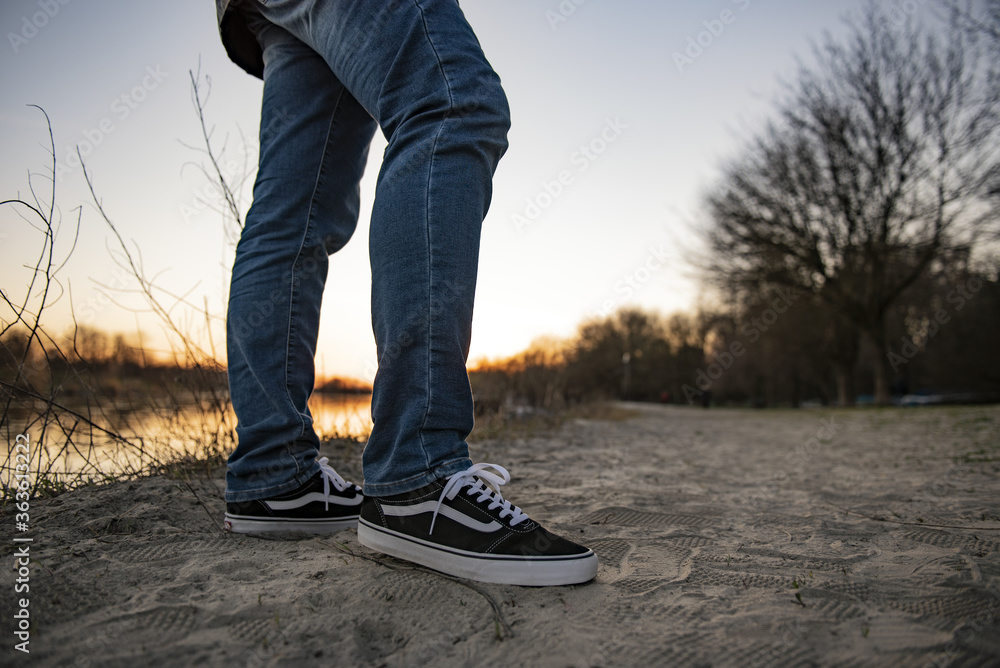 Young man wearing Vans Old Skool shoes on a beach on the river Stock Photo  | Adobe Stock