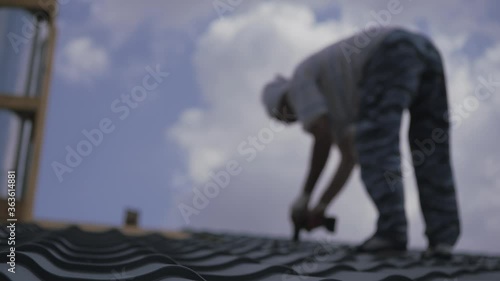 Wallpaper Mural Roofing works. The installer screws the metal tile to the roof crate. Roof construction. Torontodigital.ca
