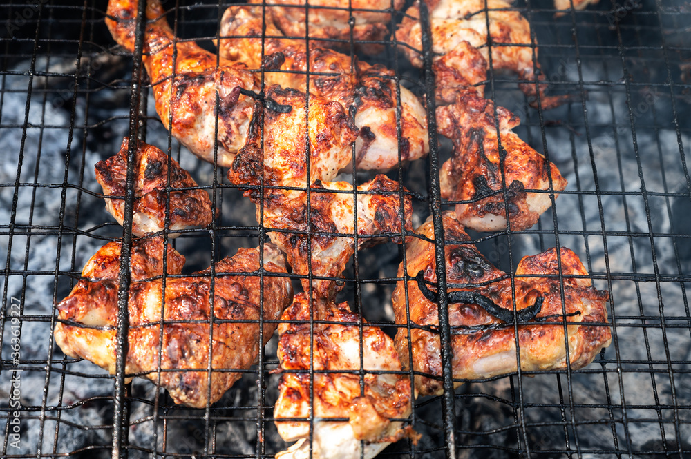 appetizing pickled chicken fried to black on a portable picnic grill. harmful fatty foods. backyard barbecue party