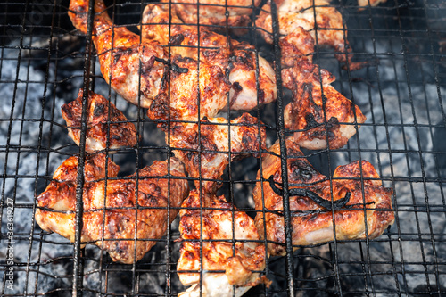 Obraz na płótnie appetizing pickled chicken fried to black on a portable picnic grill. harmful fatty foods. backyard barbecue party w salonie