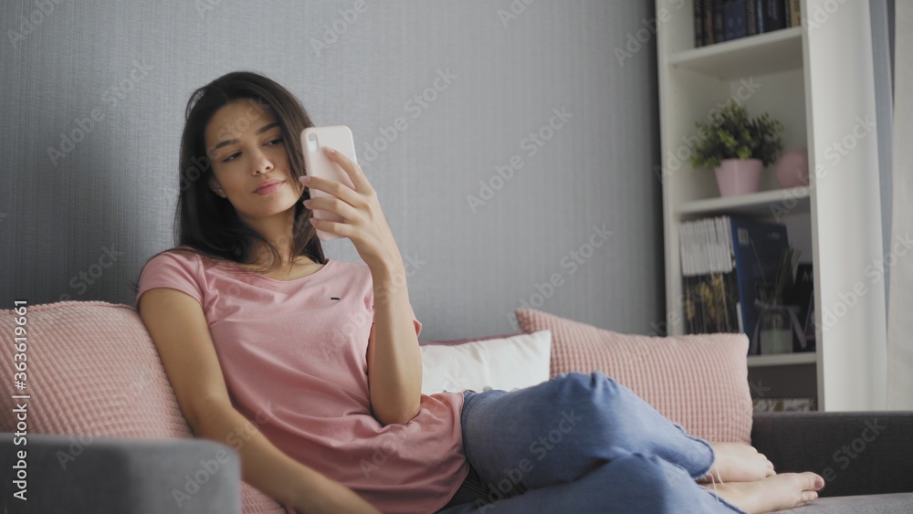 Beautiful woman taking selfie using phone while sitting on sofa at home Beautiful woman taking selfie using phone while sitting on sofa at home