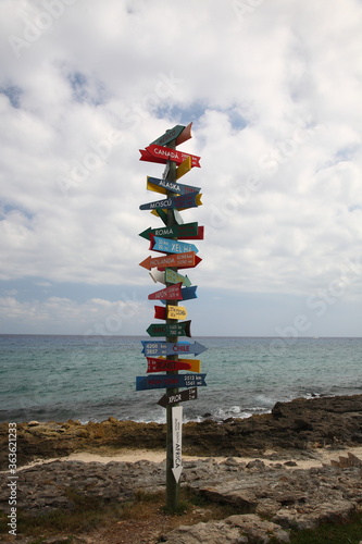 A scenic view of Direction sign with rocks and ocean under blue sky in Xcaret, playa del carmen Mexico