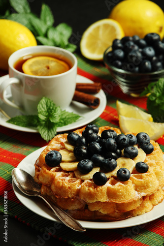Belgian waffles with blueberry and a cup of tea with lemon 
