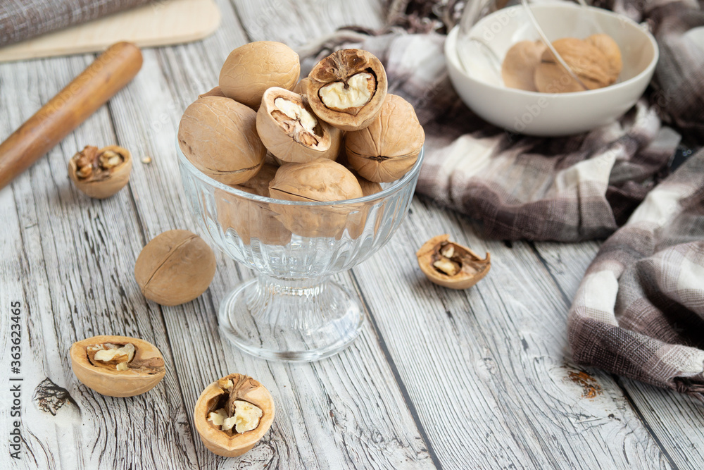 closed and split walnuts in dishes on a light wooden background, textiles, cutting Board