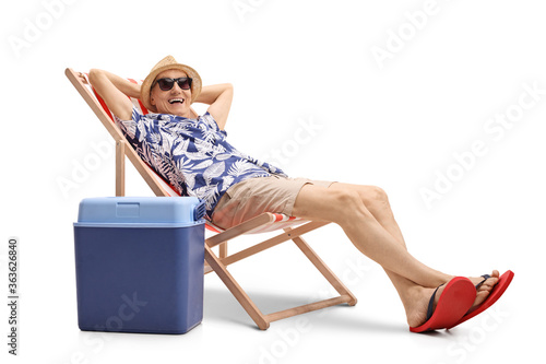 Obraz na plátne Cheerful elderly man sitting on a deckchair with a cooling box
