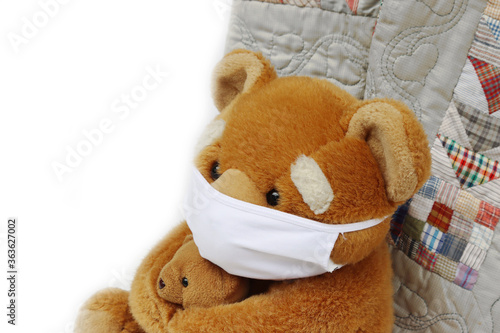 Brown teddy bear with protective medical mask made of fabric. Toy bear with mask for Covid-19 on white background