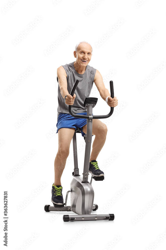 Cheerful elderly man in sportswear riding an exercise bike Cheerful elderly man in sportswear riding an exercise bike