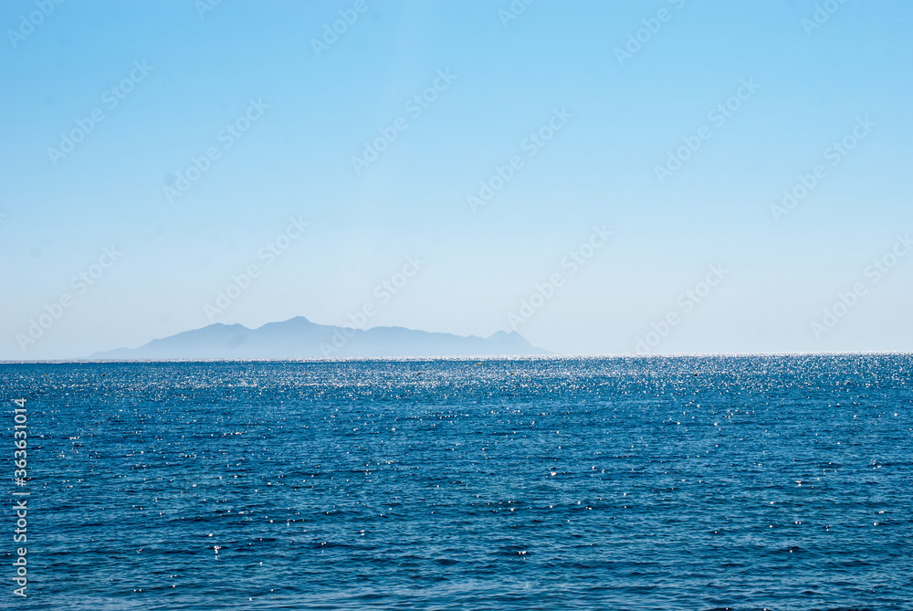 sea on the horizon island against a clear blue sky