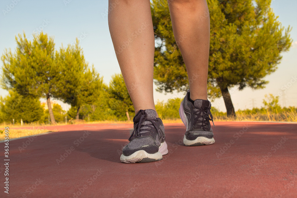 View of the legs of an athletic woman as she runs through a beautiful yellow field in the middle of a sunset