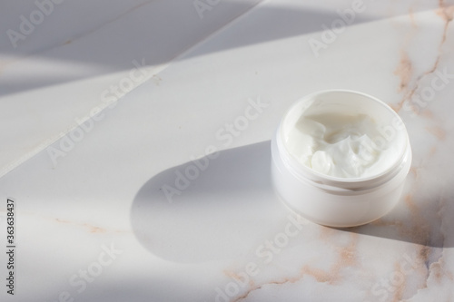 Face mask in a white jar on a marble table. Spa concept. Minimalism.