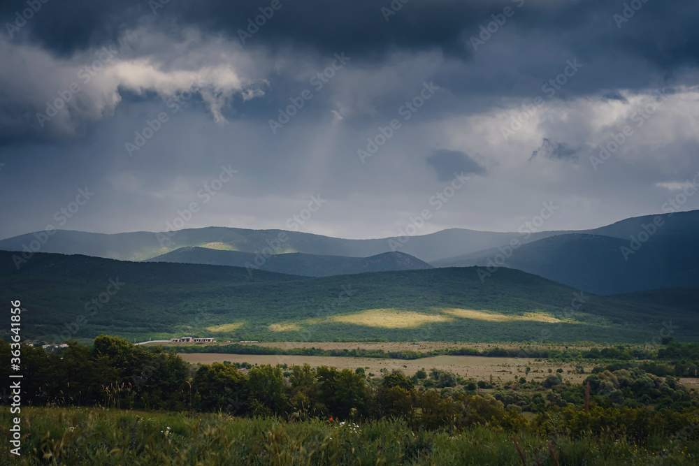 Fototapeta premium Picturesque green valley among the mountains before a storm.